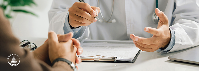 Healthcare professional holding pen over paperwork and discussing with another person