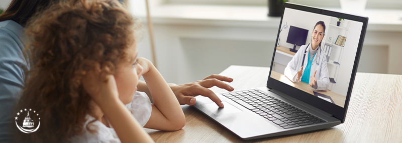 Mom and daughter speaking to doctor through video chat on laptop using telehealth services
