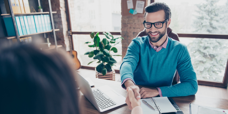 Man shaking hands with person across from him in office