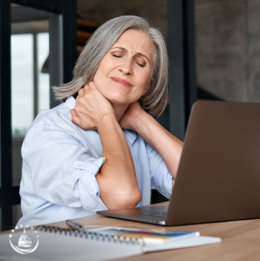 Woman clutching her neck with both hands with a look of pain on her face in front of a open laptop